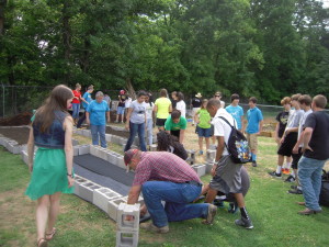 Students and teacher, Ray Evens, preparing raised garden for growing vegetables.